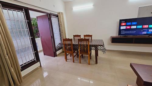 a dining room with a table and chairs and a tv at Chippy Apartments No 56 in Chennai