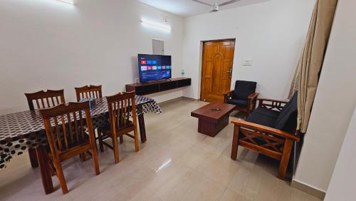 a living room with a table and chairs and a television at Chippy Apartments No 56 in Chennai