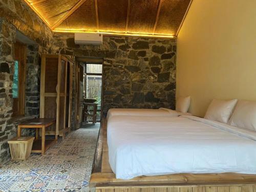 a bedroom with a large bed in a stone wall at Ha Giang Ecolodge in Ha Giang
