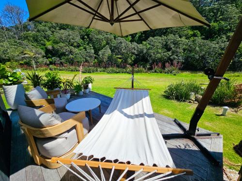 a patio with a table and an umbrella at Adventurer's Chest - Taiwawe in Hotwater Beach