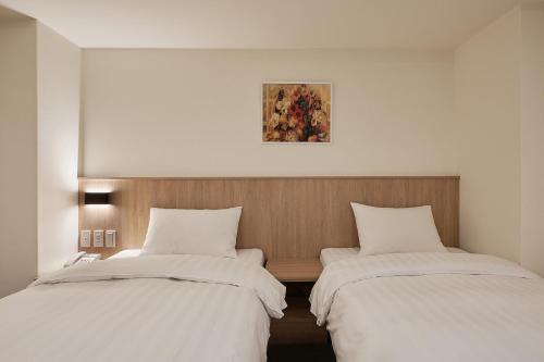 two beds sitting next to each other in a room at Nei Jiang Hotel in Taipei