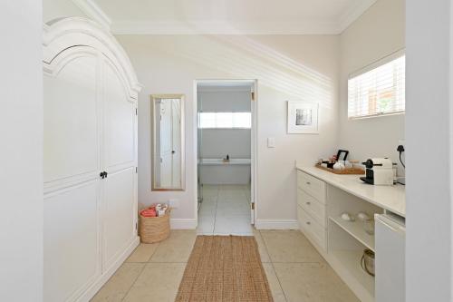 a kitchen with white walls and a hallway with a mirror at Fransvliet Guest House in Franschhoek