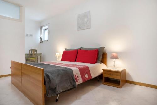 a bedroom with a large bed with red pillows at Casa Hueller Roncegno in Roncegno