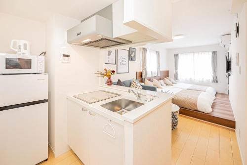 a white kitchen with a sink and a living room at New-built APT at Asakusa-Skytree area with Tranquil block in Tokyo