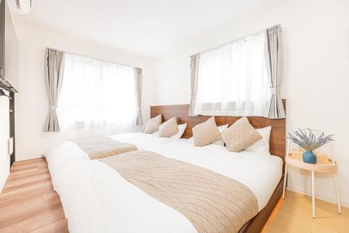 two beds in a white room with windows at New-built APT at Asakusa-Skytree area with Tranquil block in Tokyo