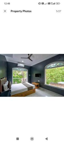 a bedroom with a large bed and two windows at Hotel Harmony By Heaven in Calangute
