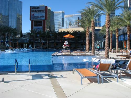a pool with chairs and palm trees and buildings at Suites at Elara Las Vegas Strip-No Resort Fees in Las Vegas