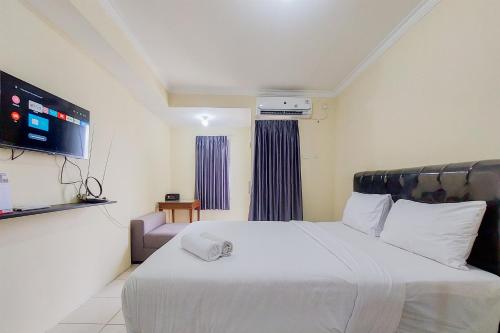a bedroom with a large white bed and a television at Cozy and Minimalist Studio Great Western Apartment By Travelio in Tangerang