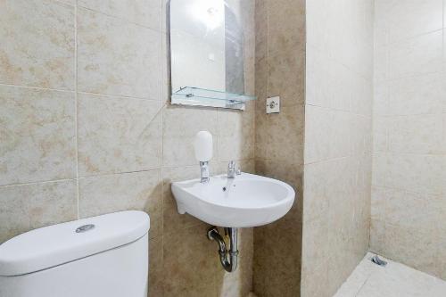 a bathroom with a white toilet and a sink at Cozy and Minimalist Studio Great Western Apartment By Travelio in Tangerang
