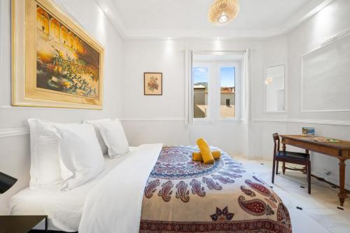 une chambre blanche avec un lit et un bureau dans l'établissement Alexandra Palace, Appartement Belle Époque Menton, vue mer, parking, à Menton