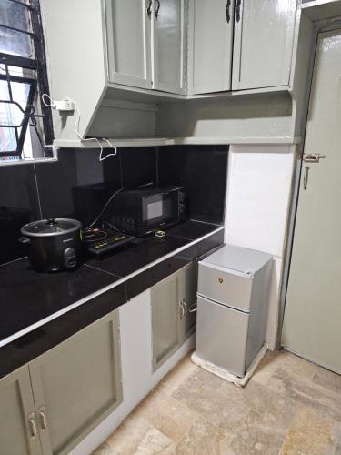 a small kitchen with a microwave and a refrigerator at Casa Feliz Apartments Baguio in Baguio
