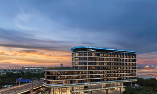 a hotel building with a sunset in the background at Hilton Shanghai Hongqiao International Airport in Shanghai