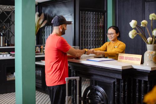 a man and a woman shaking hands at a counter at Hanoi Ancient Paradise Hotel in Hanoi