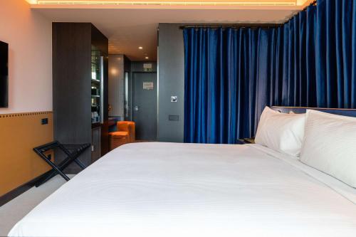 a bedroom with a large white bed with blue curtains at Cenica Porto Hotel, Curio Collection By Hilton in Porto