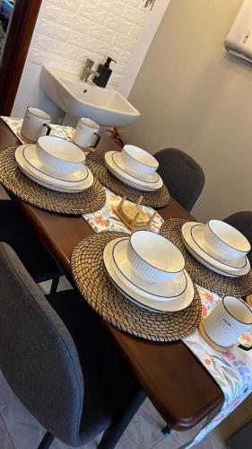 a wooden table with white plates and a sink at Gamaleo Apartment Namulanda in Namulanda