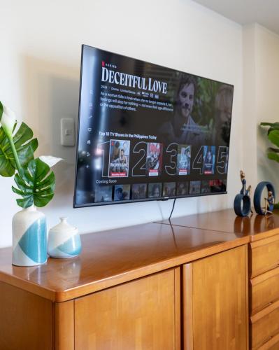 a flat screen tv sitting on top of a wooden entertainment center at 617A Condotel Near Airport &Mall with Pool,Gym,Netflix in Mactan Cebu International
