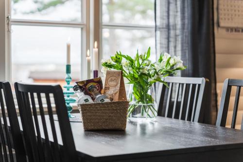 a dining room table with a vase of flowers and a candle at Guestly Homes - 1BR Countryside Cabin with Sauna in Piteå