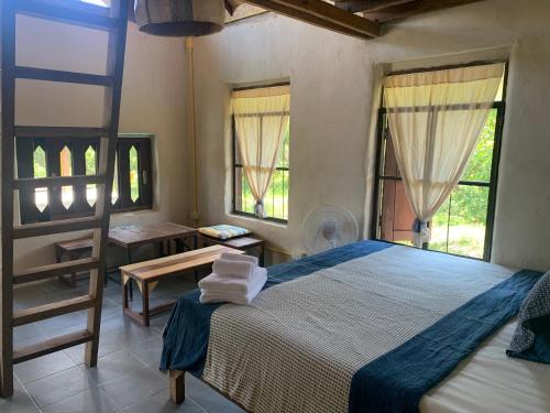 a bedroom with a bed and a table and windows at Little Forest Chiang Mai in Chiang Mai