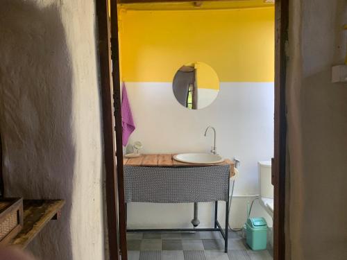 a bathroom with a sink and a yellow and white wall at Little Forest Chiang Mai in Chiang Mai