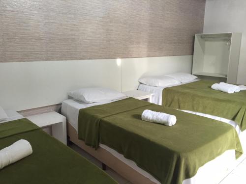 a room with three beds with green and white sheets at Pousada Villa Joia in Barra de São Miguel