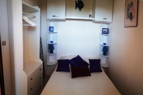 Cette petite chambre comprend un lit avec des oreillers bleus. dans l'établissement Appartement Saint Pierre la Mer 6 personnes, vue sur la mer, piscine, parking, tennis M330, à Saint Pierre La Mer