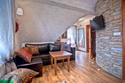 - un salon avec un canapé en cuir et un mur en pierre dans l'établissement Willa Grandeus, à Bukowina Tatrzańska