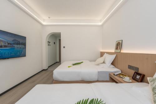 two beds in a room with white walls at Lane Wisdom Garden Hotel - Lijiang Ancient City Zhongyi Market in Lijiang