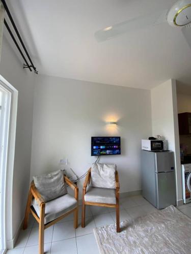 a room with two chairs and a table and a refrigerator at Fumba Town Tausi Apartments in Zanzibar City