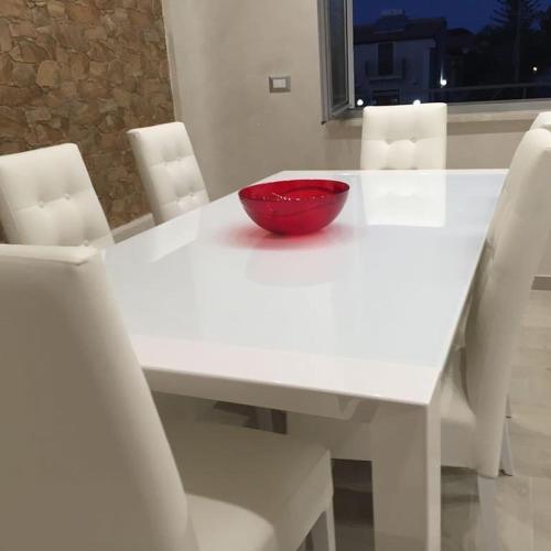 a red bowl sitting on a white table with white chairs at Villa Joel in Fontane Bianche