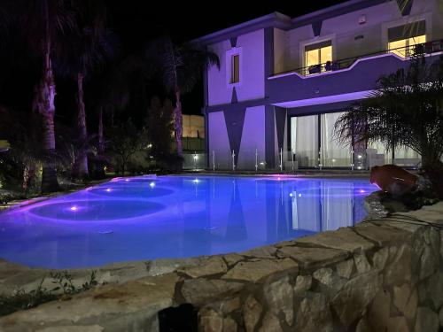 a swimming pool in front of a house at night at Villa Joel in Fontane Bianche