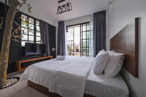 a bedroom with a white bed and a window at Cameron Highland Retreat in Tanah Rata