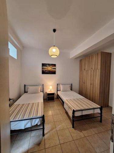 a bedroom with two beds and a light fixture at D and D Home Alonissos in Alonnisos