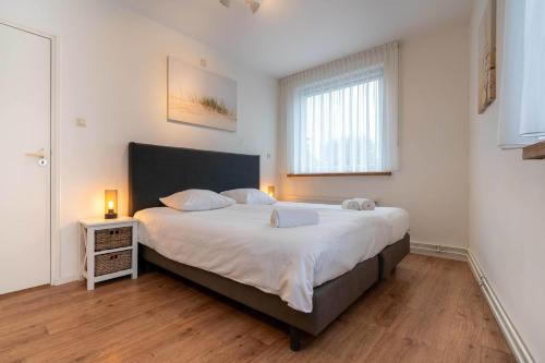 a bedroom with a large bed with two lamps on it at Hello Zeeland - Apartment Noordstraat 30 in Zoutelande