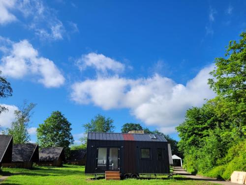 a black tiny house in a field with trees at Bigge Elements Tinyhaus 5 "Wasser" in Olpe