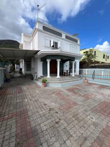 a large white house with a brick courtyard at 3 BR Villa Agape with Pool in Tamarin