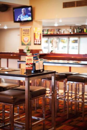 a dining room with tables and chairs and a tv at Nightcap At Balaclava Hotel in Cairns