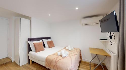 - une chambre avec un lit, une télévision et un bureau dans l'établissement 135 Suite Franck - Charmant Studio à Paris, à Paris
