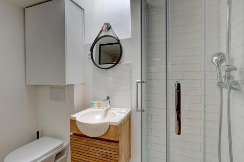 une salle de bain avec un lavabo et une douche avec un miroir dans l'établissement 135 Suite Franck - Charmant Studio à Paris, à Paris