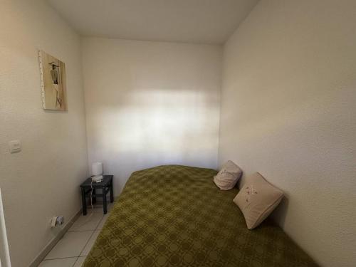- une petite chambre avec un lit et une couverture verte dans l'établissement STUDIO BIS Santa Reg, à Calvi