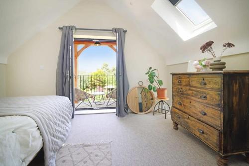 a bedroom with a bed and a dresser and a window at Contemporary Cottage & Garden in Dorset in Blandford Forum