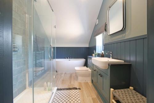 a bathroom with a tub and a sink and a toilet at Contemporary Cottage & Garden in Dorset in Blandford Forum