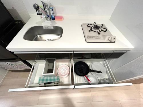 a white kitchen counter with a sink and dishes at Shinjuku Tokyo Holiday Hotel in Tokyo