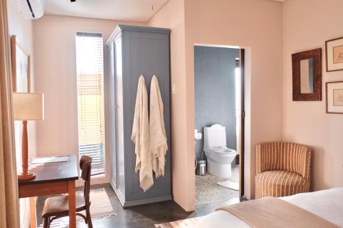 1 dormitorio con cama, escritorio y aseo en Rose Cottage, en Ciudad del Cabo