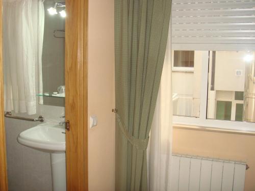 a bathroom with a sink and a toilet and a window at Hotel PAYRO in Santiago de Compostela