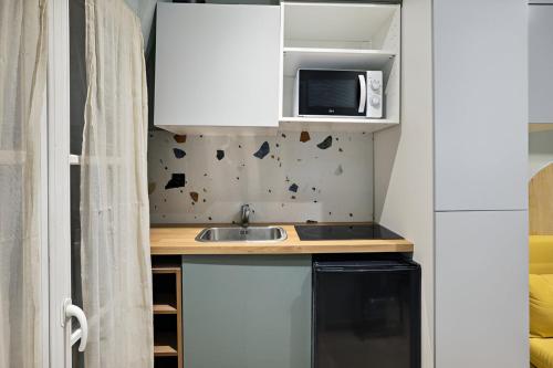 une petite cuisine avec un évier et un micro-ondes dans l'établissement 503 Suite Pergolèse - Charmant Studio in Paris, à Paris