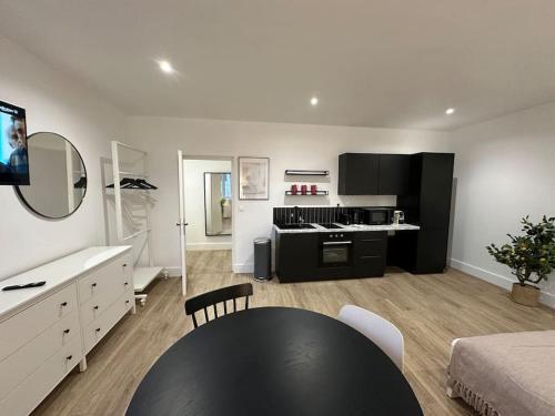 un salon avec une table noire et une cuisine dans l'établissement Acapulco, studio spacieux rénové, à Reims