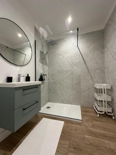 une salle de bain avec une douche avec un lavabo et un miroir dans l'établissement Acapulco, studio spacieux rénové, à Reims