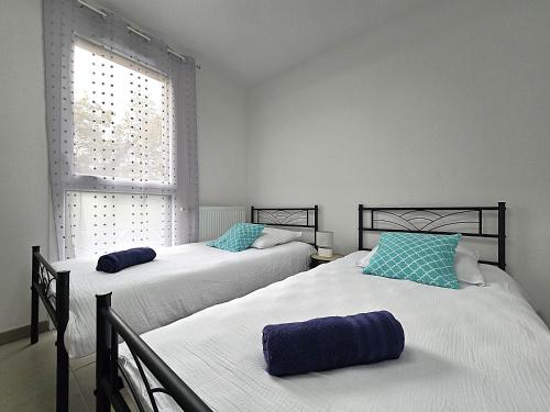 deux lits dans une chambre avec une fenêtre dans l'établissement Charmante maison 6 personnes - 5 min à pied zone commerciale Sapiac - 3 chambres - 4 lits - Jardin et terrasses privés - Parking gratuit sur place, à Montauban