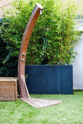 a wooden chair sitting in the grass next to a bush at Villa Meyzieu Grand Large in Meyzieu