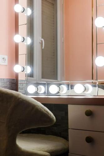 a bathroom with a mirror and a sink with lights at Villa Meyzieu Grand Large in Meyzieu
